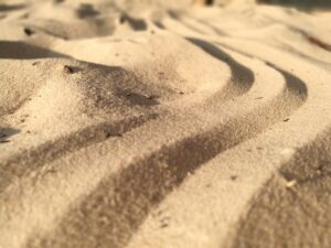 close up of sand with sweeping waves formed to look like miniature dunes