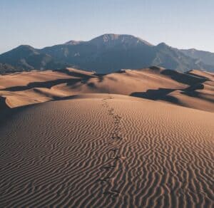 Footprints in the desert leading to mountains